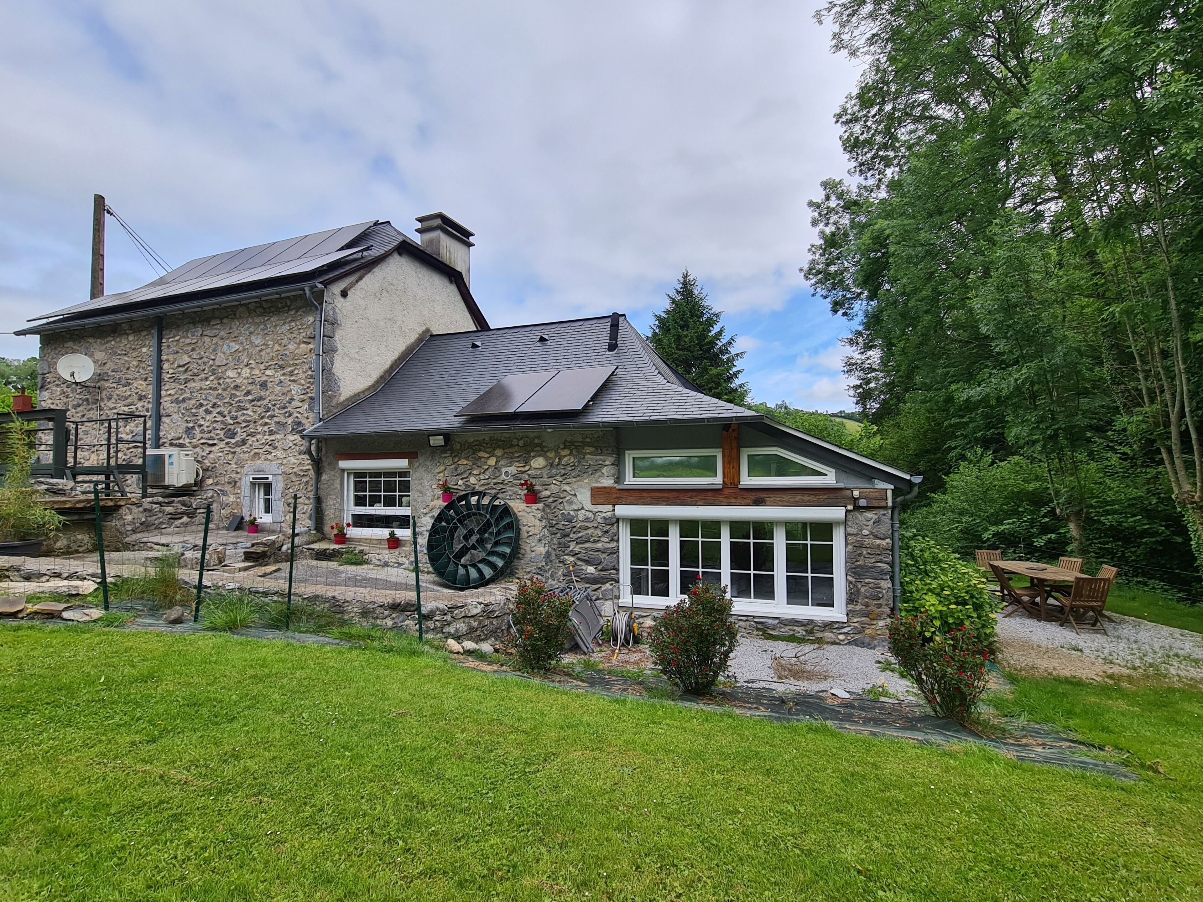 A stone house with a large window, a satellite dish, and a circular window.
