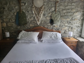 Ein Bett mit weißer Bettwäsche, einem Holz-Kopfteil und zwei Nachttischen mit Lampen.