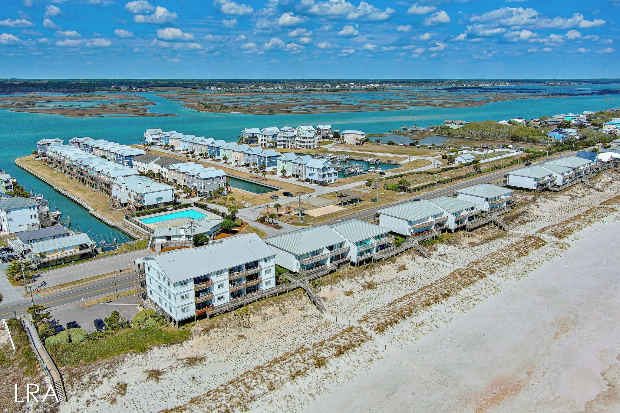 A coastal hotel with multiple buildings, a swimming pool, and a beach area.