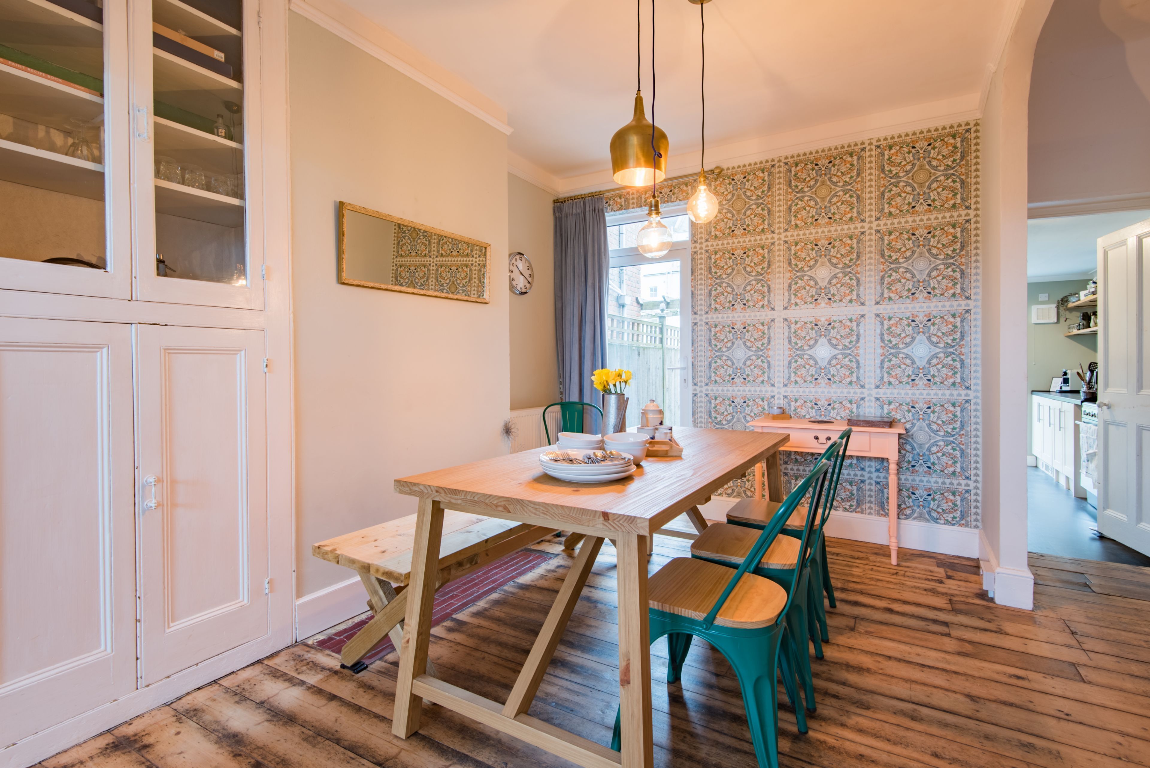 A dining area with a wooden table, chairs, and a hanging light fixture.