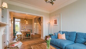 A living room with a blue sofa, wooden coffee table, and a vase of flowers. - Whispering Waves, Hythe (Hythe)