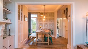 A dining area with a wooden table, chairs, and a hanging light fixture. - Whispering Waves, Hythe (Hythe)