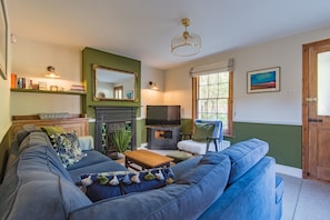 A living room with a sofa, television, fireplace, and a large mirror. - Pebble Beach Cottage (Kingsdown)