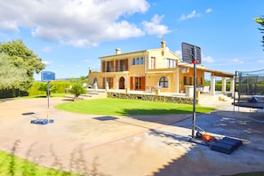 A two-story house with a basketball court, outdoor seating, and a stone wall. - Tranquil Binissalem Country Home with Pool (Binissalem)