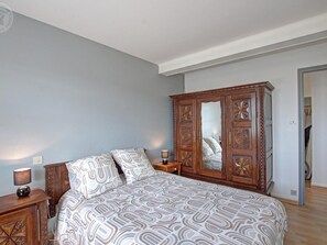 Ein Schlafzimmer mit einem Bett, einem Holzschrank, einem Nachttisch und einer Lampe.