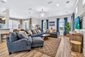 A modern living room with a sectional sofa, a coffee table, and a dining area with wooden chairs. - Sugar Palm | Steps to Beach, Heated Pool, FREE Golf Cart, Game Room, Bunk Rooms (Miramar Beach)