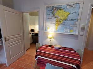 A small dining area with a map of South America on the wall, a table with a striped tablecloth, and a lamp.