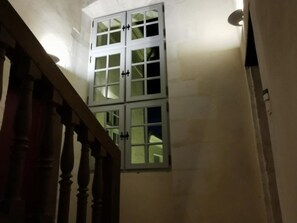 Un escalier avec une rampe en bois menant à une pièce dotée d’une grande fenêtre.