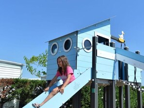 A person on a blue slide attached to a structure with circular windows. - Spacious mobile home - 6 guests (Aiguillon-sur-Mer)