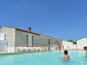 A swimming pool with stone walls, a tiled roof, and a few people in the water. - Spacious mobile home - 6 guests (Aiguillon-sur-Mer)