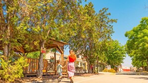 A pathway lined with trees and a wooden structure, possibly a gazebo, with a clear sky above. - Comfortable mobile home with terrace - 4 guests (Vic-la-Gardiole)
