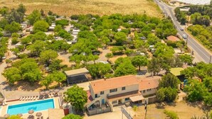 An aerial view of a residential area with houses, a swimming pool, and a road. - Comfortable mobile home with terrace - 4 guests (Vic-la-Gardiole)