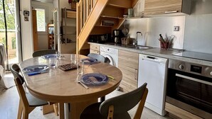 Kompakti keittiö, jossa on astianpesukone, uuni ja puinen portaikko.