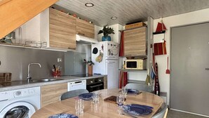 Kompakti keittiö, jossa on ruokailutila, pesukone ja mikroaaltouuni.