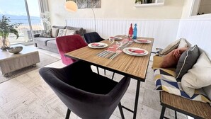 A dining area with a table set for four, a sofa, a chair, and a view of the outdoors. - Studio cabin sea view - 4 guests (Saint-Raphaël)