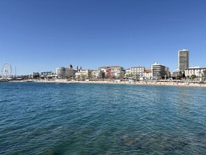 Eine Küstenstadtlandschaft mit Strand, Riesenrad und verschiedenen Gebäuden.