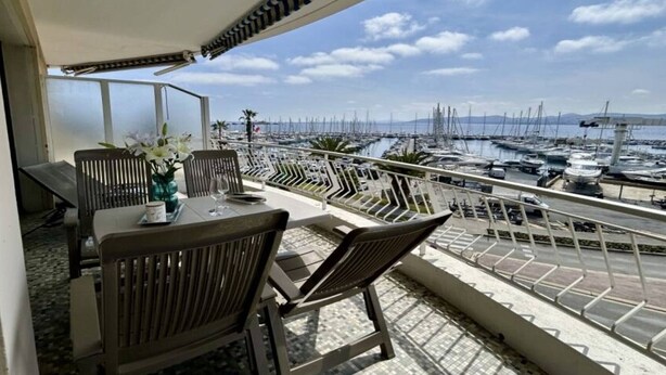 A balcony with a view of a marina, a table with chairs, and a vase with flowers. - Studio cabin sea view - 4 guests (Saint-Raphaël)