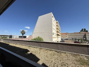 Ein Gebäude mit flachem Dach, ein Parkplatz mit mehreren Autos und einem klaren, blauen Himmel.