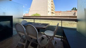 A balcony with a table and chairs, a view of a building, and a clear sky. - Studio near fish market - 4 guests (Arcachon)