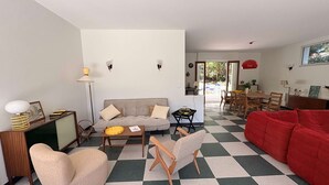 Ein Wohnzimmer mit einer Couch, einem Sessel und einem Essbereich mit Tisch und Stühlen.