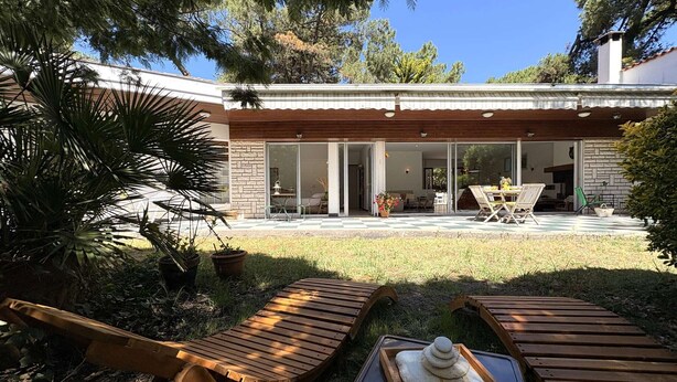Ein modernes Haus mit Terrasse, Holzliegen und Essbereich.