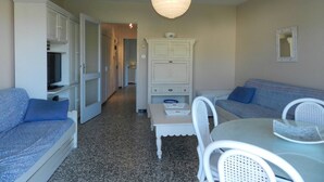 Um espaço compacto com sofá, mesa de jantar e armário.