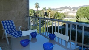 Uma varanda com mesa, cadeiras e recipientes azuis.
