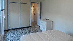 Quarto com cama, cômoda, guarda-roupa e luminária pendente.