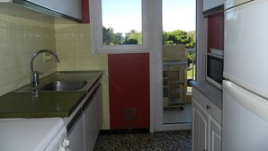 Uma cozinha compacta com janela, pia e fogão.