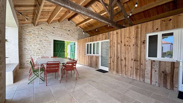 Ein rustikaler Essbereich mit einer Steinwand, Holzbalken an der Decke und einem Fliesenboden.