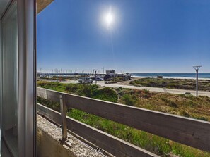 Blick auf die Küste vom Balkon mit Holzbalkon, einem klaren Himmel und einem Strand in der Ferne.