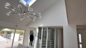 Un amplio salón con un sofá grande, tragaluces y una lámpara moderna.