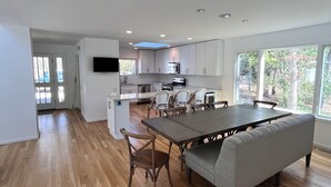Una cocina moderna con armarios blancos, una isla central y un comedor con una mesa grande y sillas.