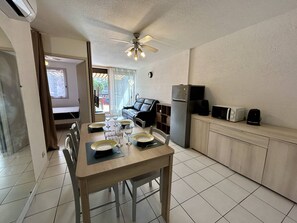 Eine kleine Küche mit Essbereich, einem Kühlschrank, einer Mikrowelle und einem Deckenventilator.