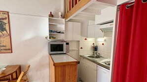 Uma cozinha compacta com micro-ondas, pia e bancada de madeira.
