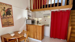 Cozinha compacta com área de refeições, micro-ondas e pia.