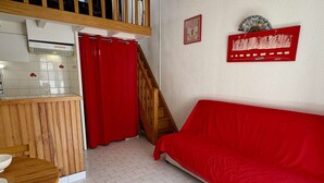 Um espaço compacto com cozinha compacta, área de refeições, sofá vermelho e escada.