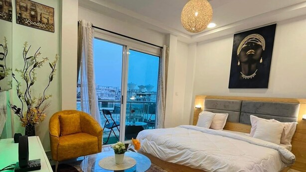 Una camera d'albergo moderna con un letto grande, una scrivania, un tavolino rotondo e vista sulla città.