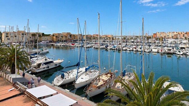 A marina with boats docked, a waterfront promenade, and buildings in the background. - Studio with terrace port view - 4 guests (Gruissan)