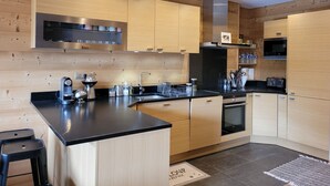 Een moderne keuken met houten kastjes, een zwart aanrecht, roestvrijstalen apparatuur en een inbouwoven.