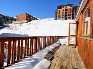 Eine Holterrasse mit schneebedeckten Stufen, die zu einem Gebäude mit Balkonen führen.