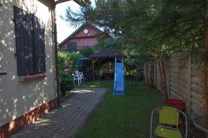 Ein Garten mit Rutsche, Laube und Terrassenbereich.