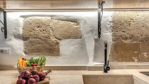A kitchen with a stone backsplash, a sink, and a fruit basket on the counter. - La Cummarizza - Le Case di Valentina (Gallipoli)