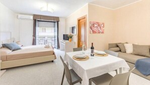 Et hotelværelse med seng, spisebord, sofa og fjernsyn.