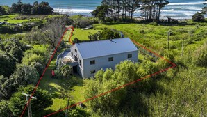 Una casa amb teulada blava, envoltada de vegetació verda i vista a l'oceà.