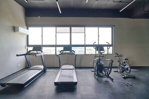 Un gimnasio con cintas de correr, una elíptica y una bicicleta estática.