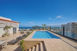 A rooftop pool with a clear view of the ocean and cityscape. - ®{Niza~City~Tower} @DowntownSD +Pool+Gym+Balcony (Santo Domingo)