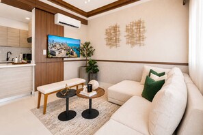 Una sala de estar moderna con un sofá, un banco, una mesa de centro y un televisor que muestra un paisaje urbano.