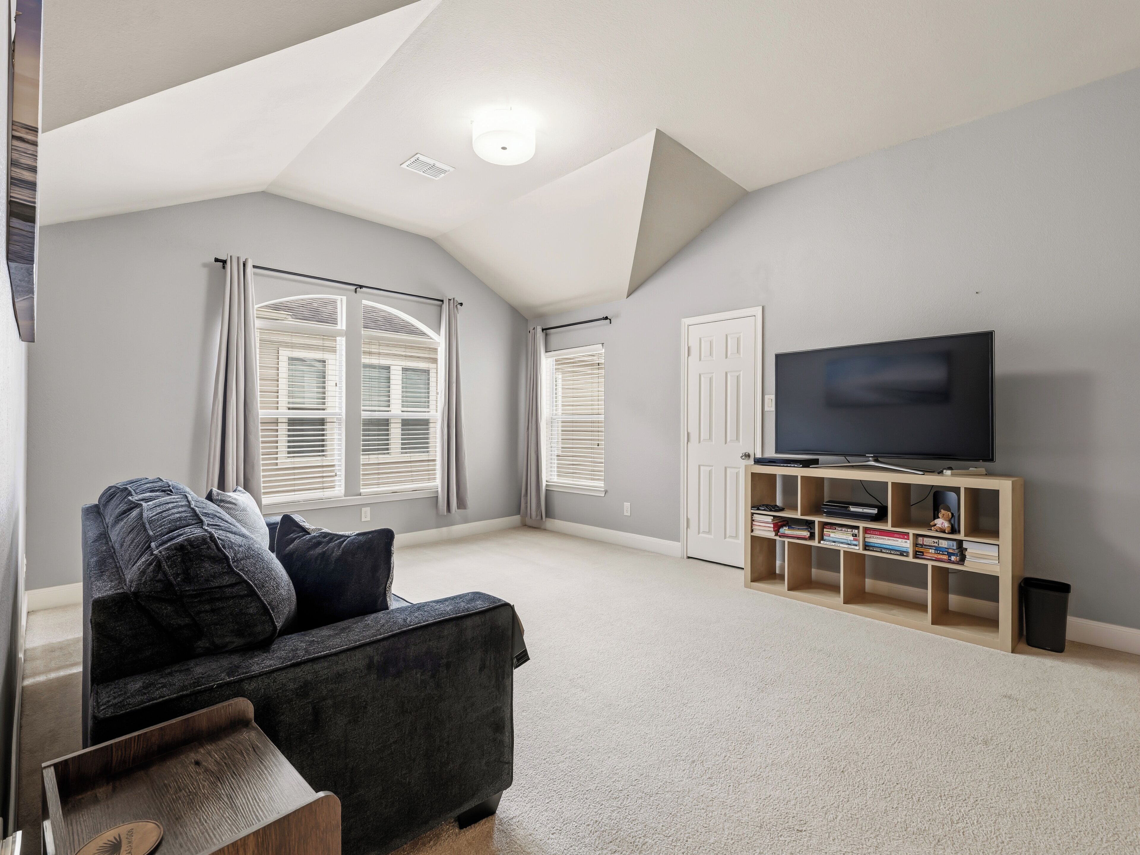Unwind in this serene living space featuring soaring vaulted ceilings and natural light streaming through oversized windows. Your home away from home boasts plush seating and a large TV for cozy evenings in.