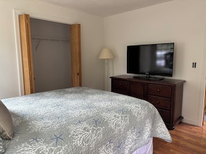 Ein Schlafzimmer mit einem Bett, einem Fernseher, einem Schminktisch und einem Kleiderschrank.